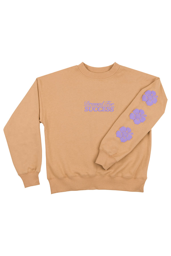 Beige sweatshirt with purple text and floral designs on a white background