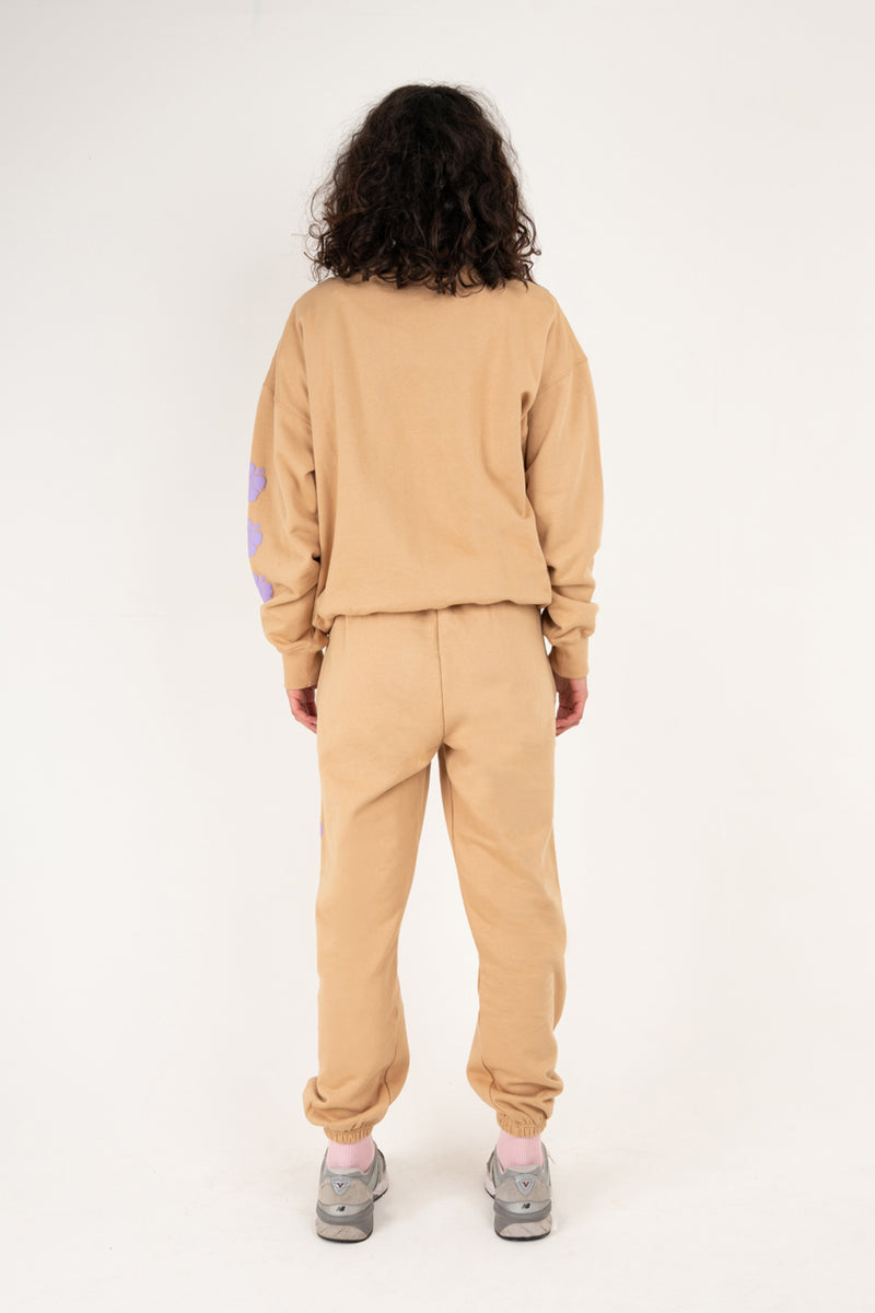 Person wearing a beige tracksuit on a white background