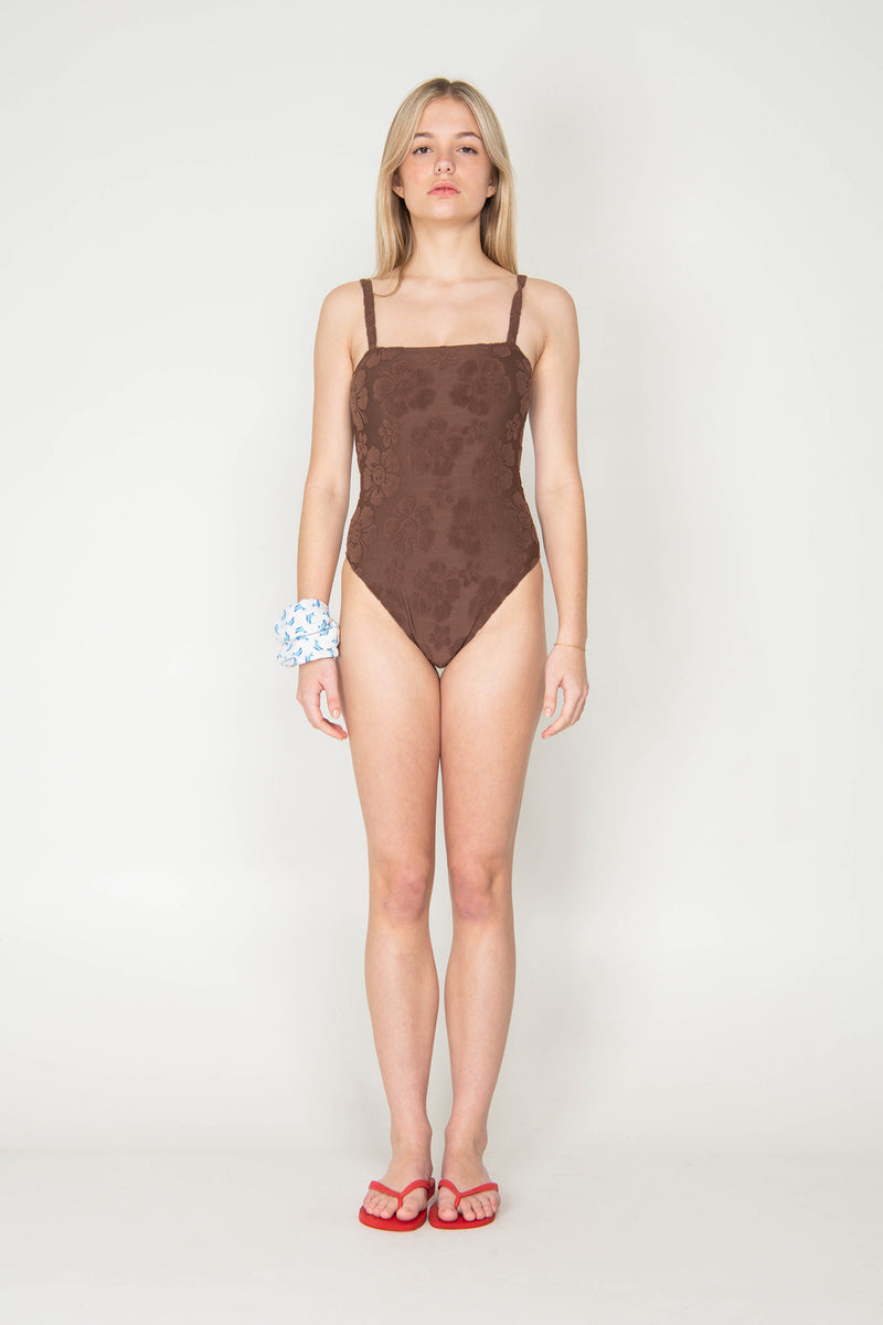 Woman wearing a brown swimsuit on a white background