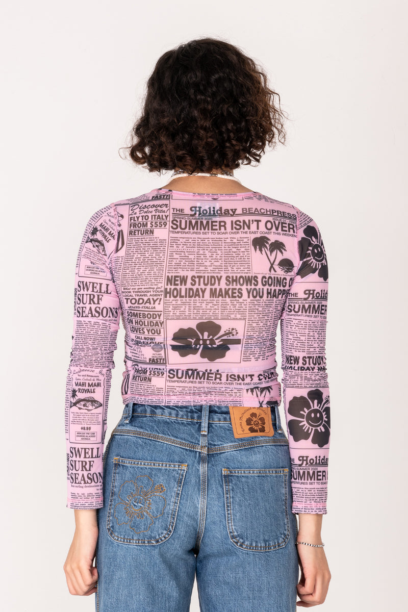 Person wearing a long-sleeve shirt with a pink and black pattern, standing against a white background.