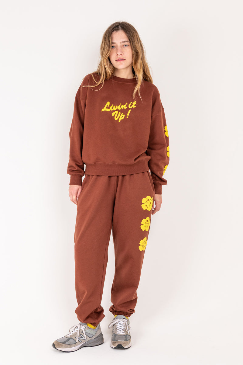 Person wearing a brown sweatshirt and pants with yellow text and graphics on a white background