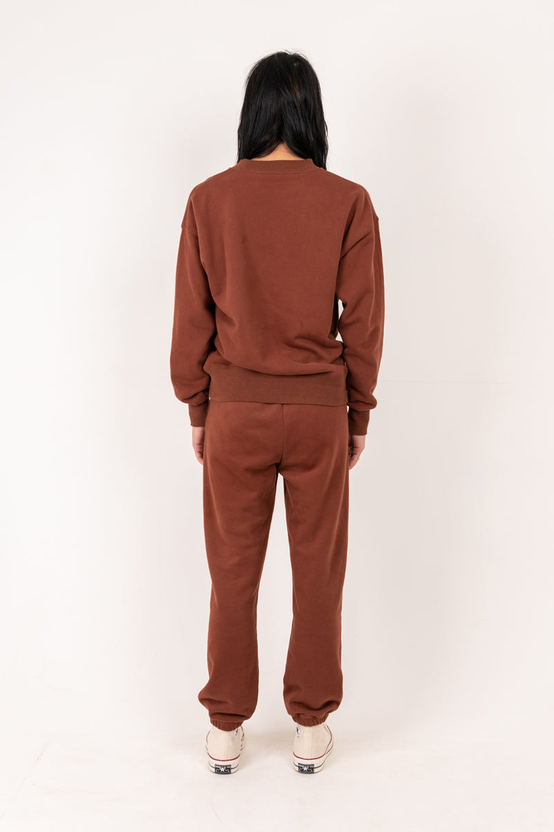 Person wearing a brown tracksuit against a white background